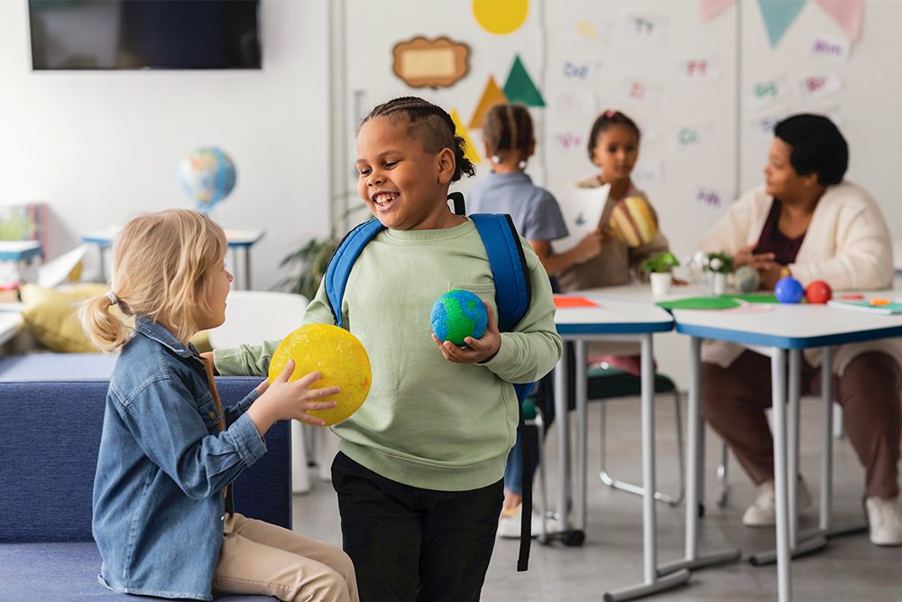 Duas alunas do ensino fundamental com diferentes características físicas trabalhando juntas na sala de aula. 