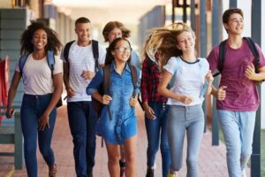 grupo de adolescentes caminhando animados no ambiente escolar.