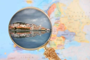 Uma lupa revela uma bela paisagem de cidade à beira de um rio com reflexos, destacando viagem e exploração em um fundo de mapa do mundo.
